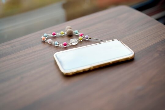 Colorful Phone Case and Beaded Strap on Wooden Table