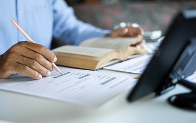 asian man checking business document find knowledge in book using tablet to working online via internet technology, close up shot