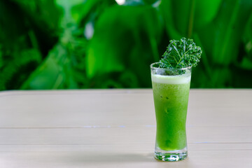 a glass of fresh green smoothie kale juice drink on the table in cafe