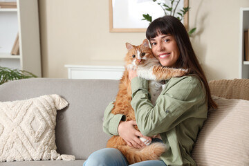 Young woman with cute ginger cat on sofa at home