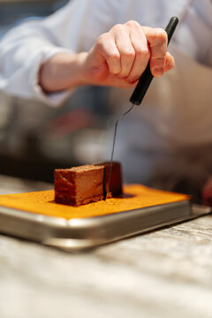 Chef slicing chocolate dessert on cutting board