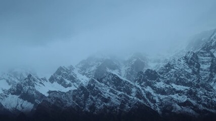 Telephoto zoom of Annapurna mountain face with deep snow and craggy rocks, severe winter weather conditions in the Himalayas of Nepal, extreme nature background for adventure themes