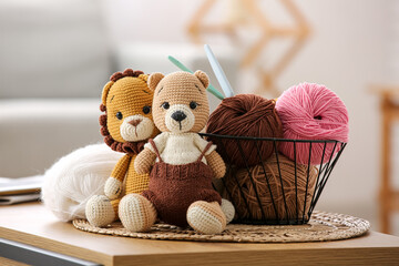 Basket with yarn, crochet hooks and knitted toys on coffee table at home