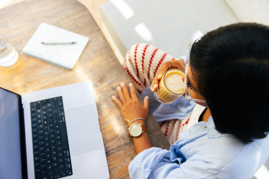 Woman sips coffee while working on a laptop
