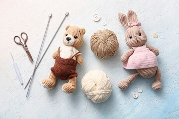 Knitted toys with yarn and knitting tools on light blue background