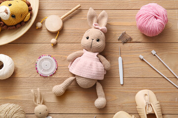 Knitted toys with yarn and knitting tools on wooden background