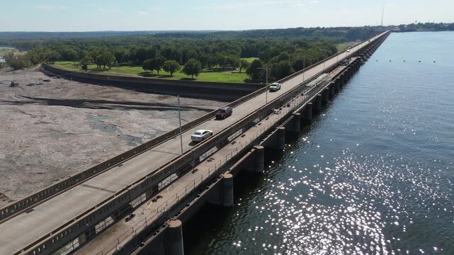 Pensacola Dam spillway and reservoir water flowing through northeastern Oklahoma, aerial pullback as cars cross on road