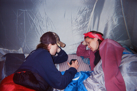 Two People Relaxing Inside a Tent with a Smartphone