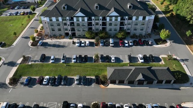 Drone backwards shot of parking cars in front of luxury multi family unit house in USA. Sunny day in autumn season. Upper class residential area in suburbia.