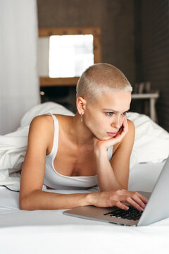 Woman Using Laptop in a Cozy Bedroom Setting at Home