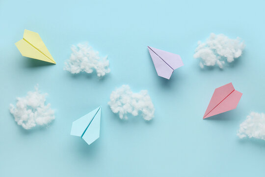 Colorful paper planes with cotton wool clouds on blue background