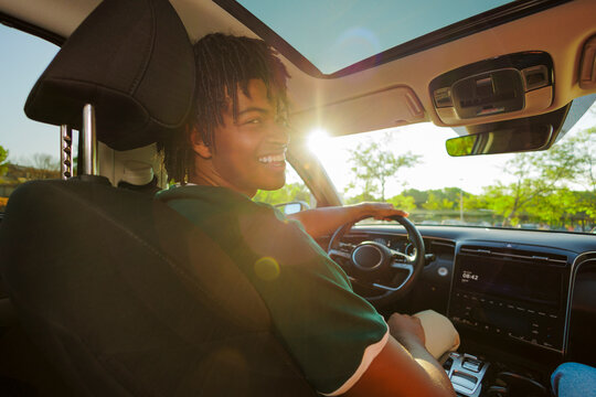 Man driving car and smiling at sunset with sun flare