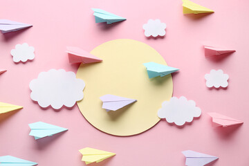 Colorful paper planes with sun and clouds on pink background