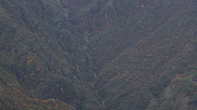 Rugged vertical landscape of high altitude mountain terrain, steep cliffs with grass and rocky soil in Nepal, landslide prone area in the Himalayas nature footage
