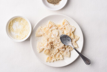 Farfalle pasta with white cream cheese sauce and black pepper, Italian food on a white plate