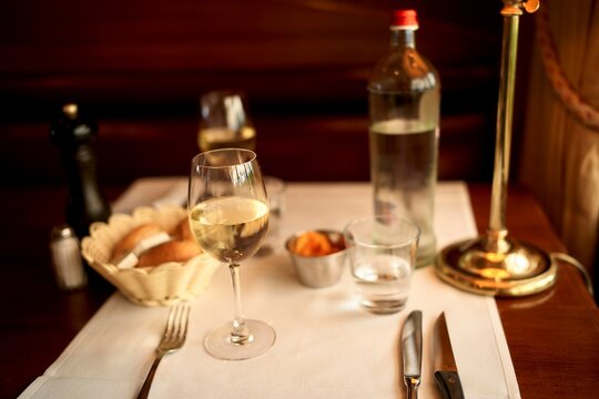 Elegant Dining Setup With White Wine and Fresh Bread Rolls