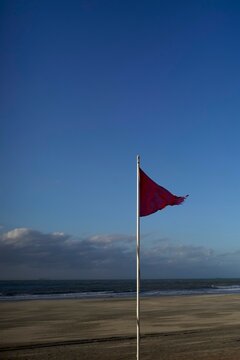 Red Flag Warning on a Beach Under a Clear Blue Sky