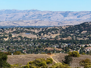 Scenic view from Almaden Quicksilver County Park overlooking San Jose, California, with dry golden hills, green trees, and distant mountain ridges under clear blue sky