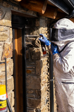 Professional fumigating a hidden wasp nest in the wall of a balcony