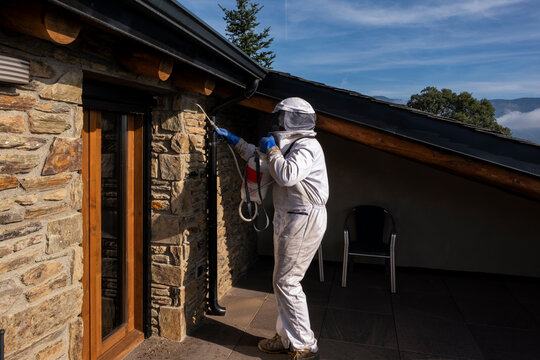 Professional fumigating a hidden wasp nest in the wall of a balcony