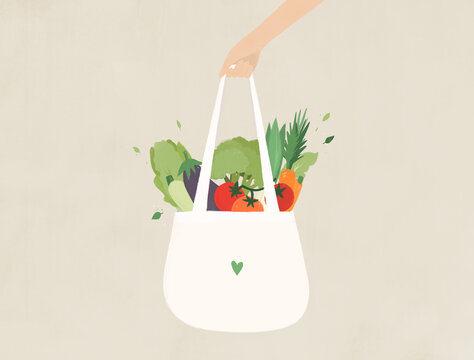 Hand holding an eco bag with organic vegetables