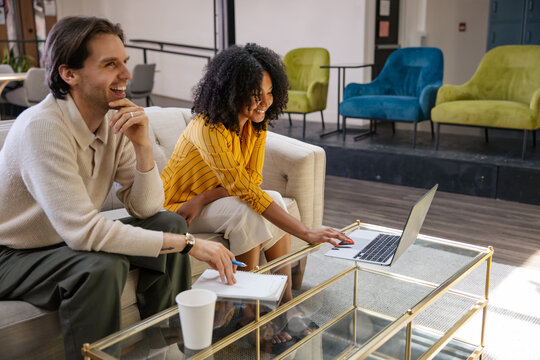 Two colleagues smiling during a collaborative meeting with a laptop 