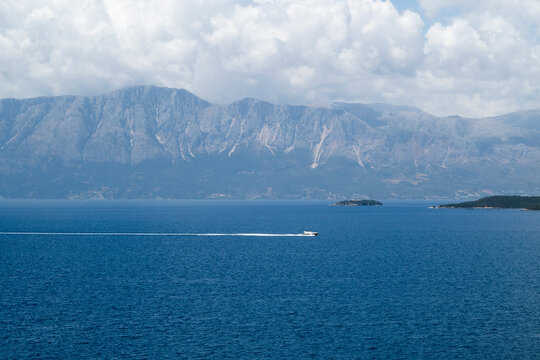 Boat in the sea, mountain and big white cloud on a blue sky