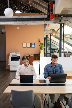 Two professionals working at shared desks in a modern open space