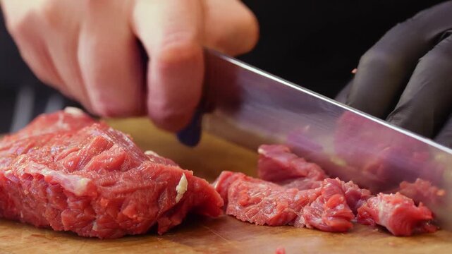 Hands of skilled butcher slicing red meat with precision in a professional environment