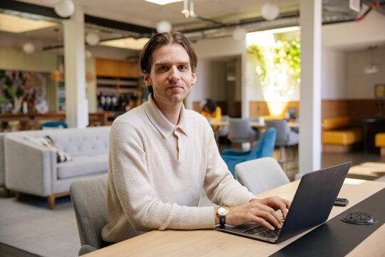 Professional man working on laptop in modern coworking