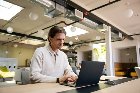 Young professional working on laptop in a modern co-working space