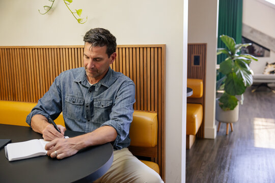 Man writing in notebook at modern cafe with stylish wood details