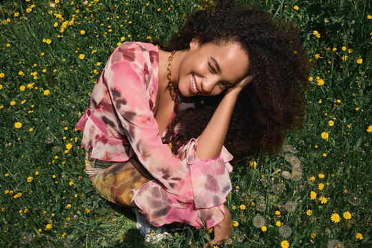 Woman sitting in field smiling with head resting on hand