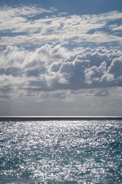 Sunlight reflection sparkes on sea surface and sky with fluffy clouds