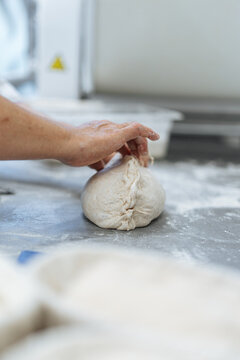 Hand shaping raw bread dough on floured counter