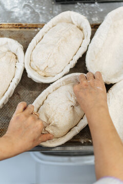 Hands placing bread dough into proofing baskets