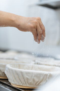 Hand sprinkling flour into proofing basket 