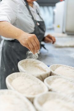 Baker sprinkling flour into proofing baskets