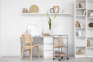 Interior of light office with workplace and gladiolus flowers