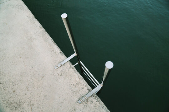 Metal railing beside calm water at midday