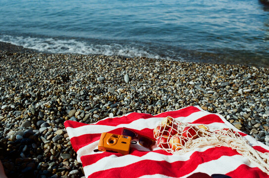 Colorful beach setup with camera, net bag and towel.