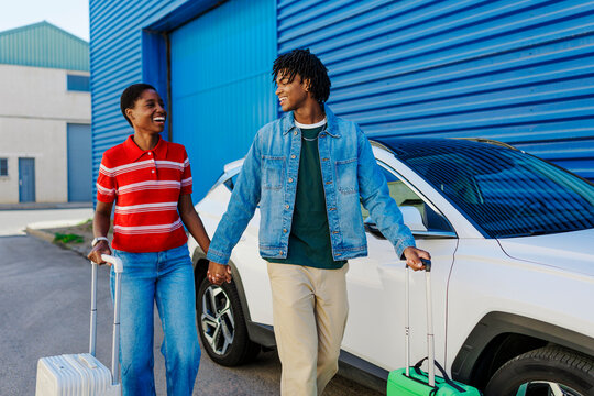 Happy couple holding hands, pulling suitcases for travel