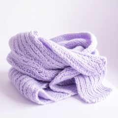 薄いラベンダーの冬トーン背景に、パステルニットスカーフが少しずらして丁寧に折り畳まれて置かれる。
淡く夢見心地の光がやわらかい編み目を優しく照らす。