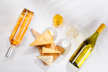 Fototapeta premium Assorted cheeses and wine bottles on white background