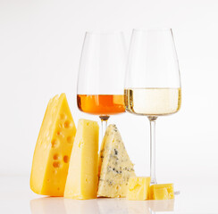 Fototapeta premium Assorted cheeses and wine glasses on white background