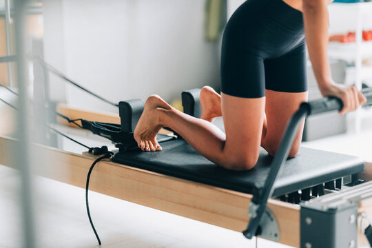 Woman Practicing Pilates on Reformer Machine in Studio