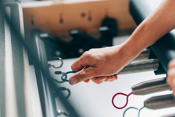 Close-Up of Hand Adjusting Springs on an Exercise Reformer Machine