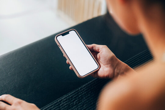 Person Holding Smartphone with Blank Screen in Indoor Setting