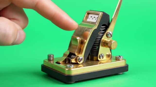 A finger depresses a brass mechanical counter on a green backdrop, showing numbers
