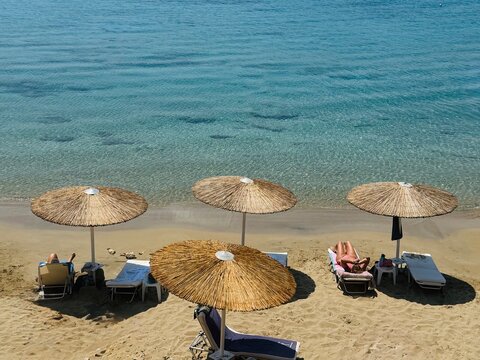 Straw beach umbrellas and calm sea at the Pefkos resort on Rhodes Island, creating a peaceful summer atmosphere